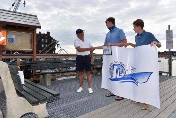 Rob Howie, Commodore of the Corinthian yacht club in Marblehead presenting Brian (left) and Noah (right)  with a green-company certificate.